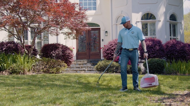 Man scooping yard in front of house
